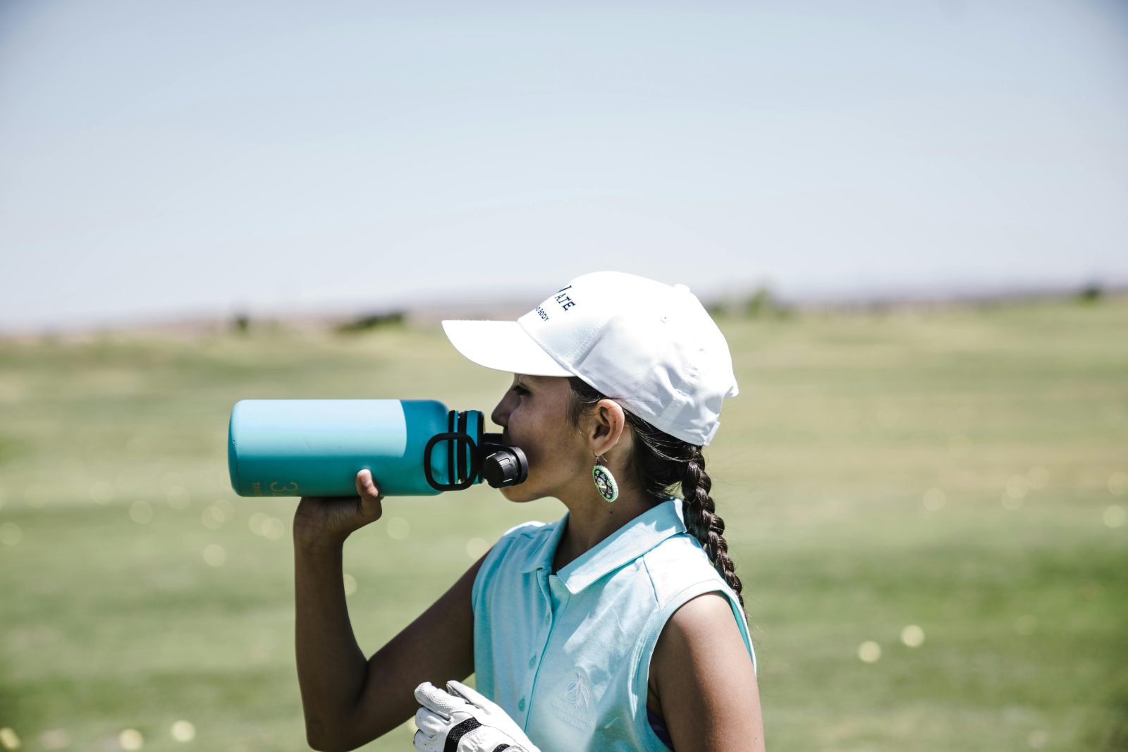 woman drinking water on golf course